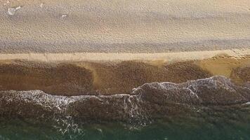 Aerial view from above on azure sea and pebbles beach. Small waves on cristal clear water surface in motion blur. Nature summer ocean sea beach background. Nobody. Holiday, vacation and travel concept video