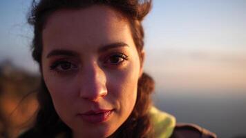 Closeup portrait of sensual young brunette woman, looking up in sky, happily outdoors isolated at blurry sea background natural bokeh in soft warm sunset backlight. video