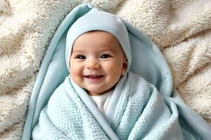 A cute baby smiling and covered with towel photo