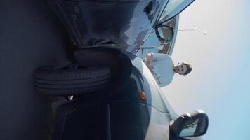 Young man has been involved in an accident and is trying to sort out his insurance and paperwork. Vertical. Slow motion. video