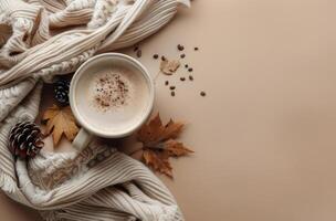 Warm Autumn Drink With Knit Blanket and Fall Leaves on Tan Background photo