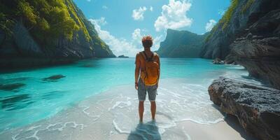 A man with a backpack is standing on the beach, gazing at the ocean photo