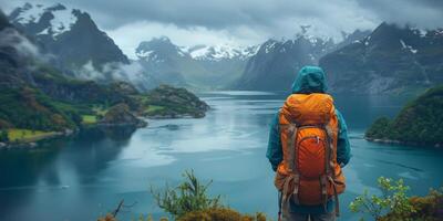A person with a backpack on top of a mountain looking at a lake photo