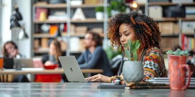 A woman is sitting at a table, using a laptop computer photo