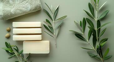 Stacked Olive Oil Soap Bars With Olive Branch and Towel on Green Background photo