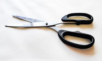 A pair of scissors with a black handle and a white background photo