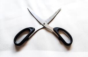A pair of scissors with a black handle and a white background photo