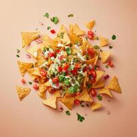 Top view of loaded nachos with cheese, guacamole, salsa, tomatoes, onions and cilantro on a peach background. Delicious and perfect snack for any occasion. photo