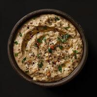 Closeup of a bowl of delicious baba ghanoush, a Middle Eastern eggplant dip, with olive oil and herbs. photo