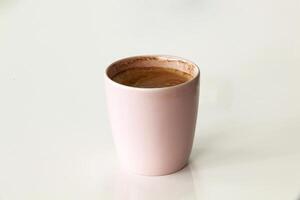 Pink coffee mug with cappuccino or latte with foam isolated on white background. Close-up photo