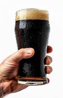 Close up of a man's hand holding a glass with dark beer isolated on a white background photo