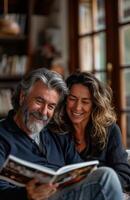 Joyful middle aged couple relaxes at home, laughing on sofa, sharing a magazine together photo