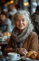 Senior woman smiling with friends, enjoying coffee and croissants at a modern cafe table photo
