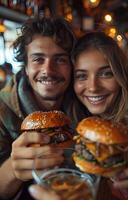 Young couple taking a selfie, enjoying burgers and beer at a restaurant, capturing a fun moment together photo