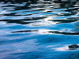 Reflection of sky on the moving water surface in the pool photo