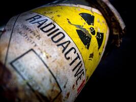 Radiation warning sign on the rusty and decay radioactive material container photo