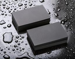two black business cards sitting on a wet surface photo