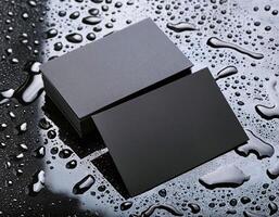 a black business card sitting on a surface with water droplets photo