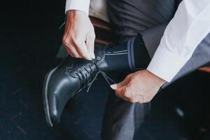 Businessman tying shoelaces, man preparing for work, groom in the morning before the wedding ceremony. photo