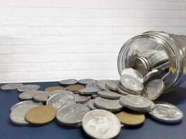 Collection of Indonesian rupiah coins on the table and a jar full of coins. Indonesian 500 rupiah coin. Coins for change, small change. Finance, investment and economics concept. photo