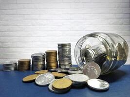 A collection of stacks of rupiah coins and savings coins in a clear glass bottle. Coins in glass jar for money saving financial concept. Finance, investment and economics concept. photo