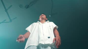 Man in white shirt with raised hands in dark teal background video