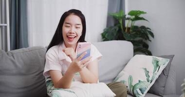 Footage dolly shot ,Carefree young woman enjoys singing while listening to music with wireless headphones through her smartphone on the sofa at home. ,Lifestyle with device technology video