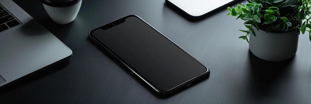 Top view of modern workspace with laptop, smartphone and plant on dark table photo