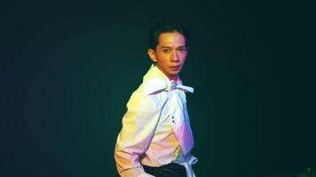 Man in white shirt with high collar under colorful lighting video