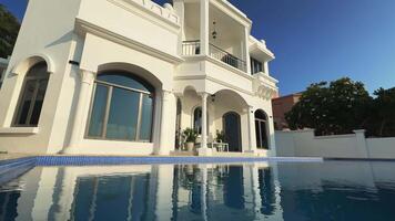 Drone flies around a private Arab villa with a swimming pool against the background of a blue cloudless sky video