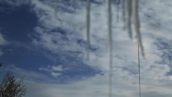 Ice icicles on the window against the background of the winter sky and the city. video