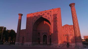 A drone flies near a complex Bibi-Khanym Mosque in Samarkand, Uzbekistan. The building is illuminated by the pink dawn light. Cloudless morning. video