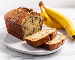 A Loaf of Banana Bread on a Plate Next to a Banana photo