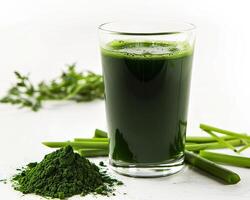 a glass of green juice next to a pile of green vegetables photo