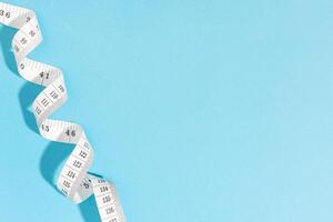 Measuring tape on blue background with copy space. Weight or length concept photo