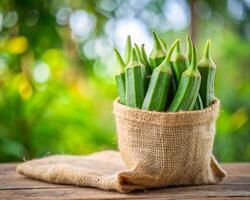 fresh green okra in a sack on a wooden table photo