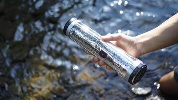 Person Holding Portable Water Purifier Bottle by a Rocky Stream photo