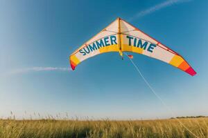 Colorful kite flying high in the sky over a field on a sunny summer day photo