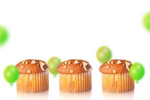 Muffins and green balloons on white background with space for text. photo