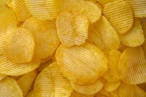 Close-up view of abundant crispy potato chips filling the frame for a textured background photo