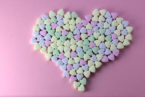 Multicolored heart-shaped candies sprinkled with sugar arrayed on a textured 1 photo