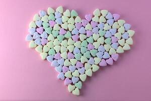 Multicolored heart-shaped candies sprinkled with sugar arrayed on a textured photo