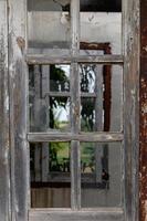 Window with broken glass in old building Wooden window frame with partially broken glass in old abandoned brick building photo
