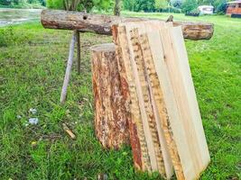 Planks and logs lie on the grass by the river, seasoning for building a raft. photo