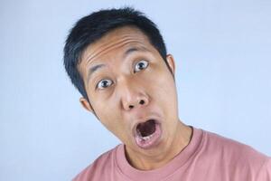 Funny facial expression young asian man shocked looking at camera, isolated on white background photo