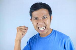 angry facial expression of asian man while making strong hand gesture, isolated on white background photo