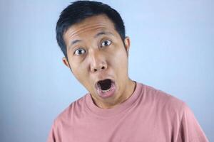Funny facial expression young asian man shocked looking at camera, isolated on white background photo