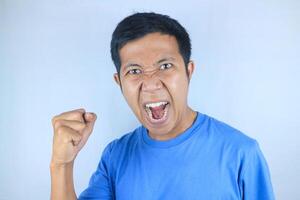 angry facial expression of asian man while making strong hand gesture, isolated on white background photo