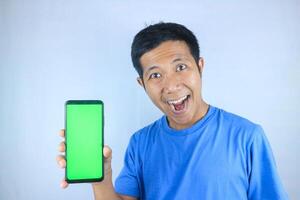 Young asian man smiling while showing an empty phone screen on white background, looking at camera photo