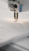 Capturing a detailed shot of a sewing machine working on fabric in a textile factory video
